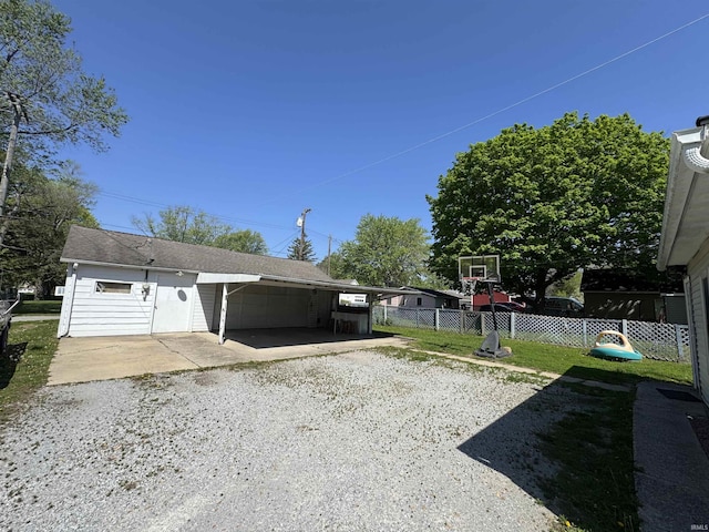 view of yard featuring fence, a carport, and driveway