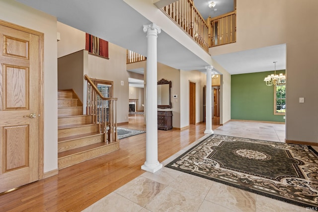 entryway with ornate columns, a high ceiling, stairs, baseboards, and wood finished floors