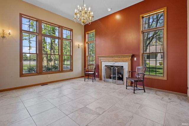 living area featuring a chandelier, baseboards, and a premium fireplace
