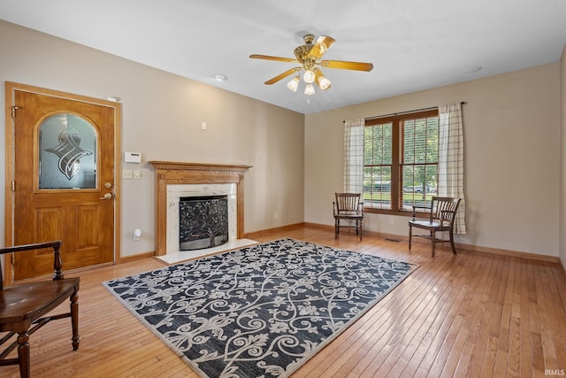 living area featuring hardwood / wood-style floors, a fireplace, ceiling fan, and baseboards