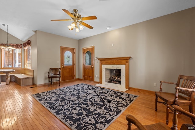 living area featuring hardwood / wood-style floors, ceiling fan, a fireplace, and baseboards