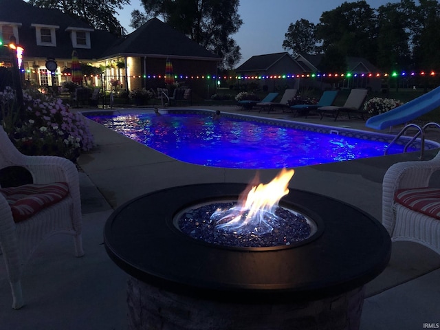 view of pool with a water slide, a gazebo, a fire pit, a patio area, and a fenced backyard