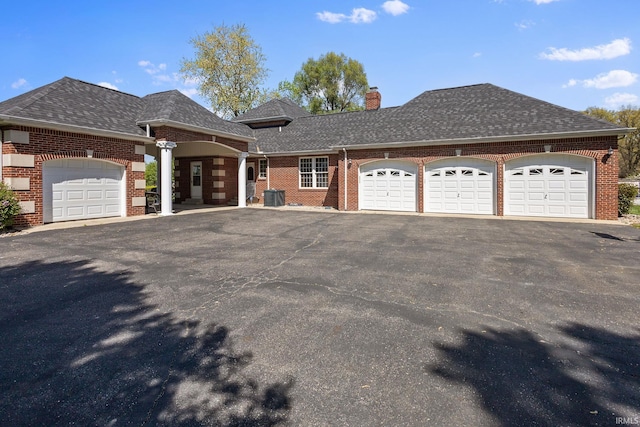 view of front of house with brick siding, a garage, a chimney, driveway, and roof with shingles