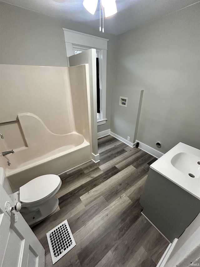 full bath with ceiling fan, toilet, wood finished floors, tub / shower combination, and vanity