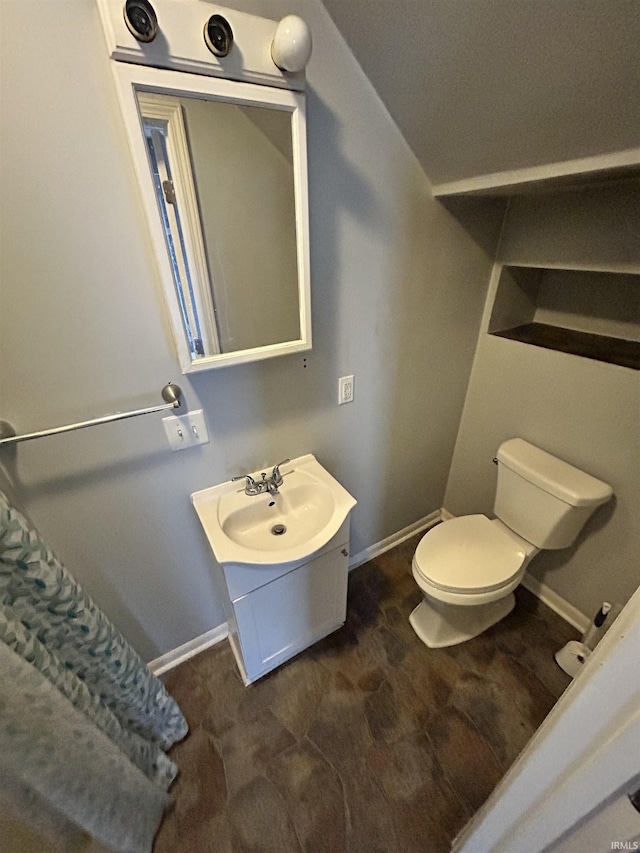 bathroom with toilet, vanity, and baseboards