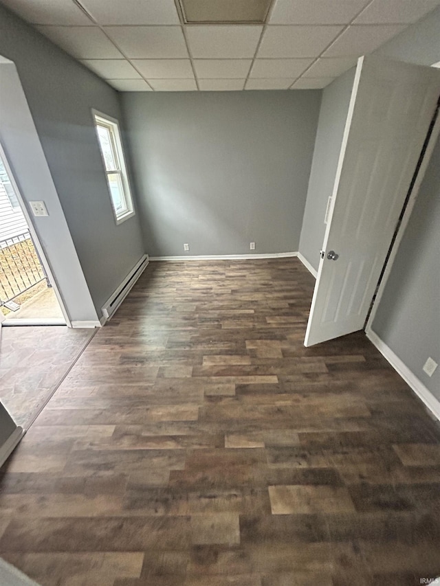 spare room featuring a baseboard radiator, a paneled ceiling, dark wood-type flooring, and baseboards