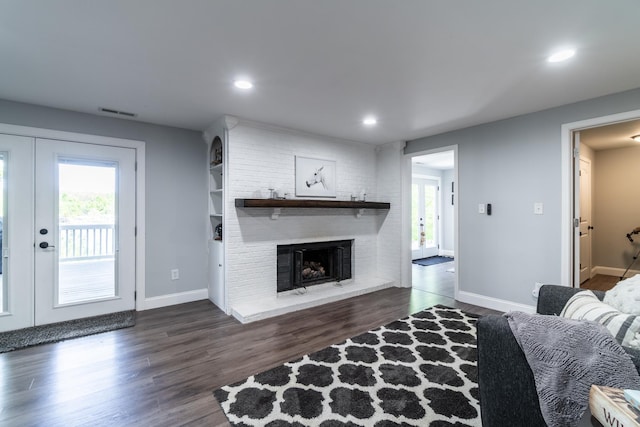 living area featuring a brick fireplace, french doors, dark wood-style floors, baseboards, and recessed lighting
