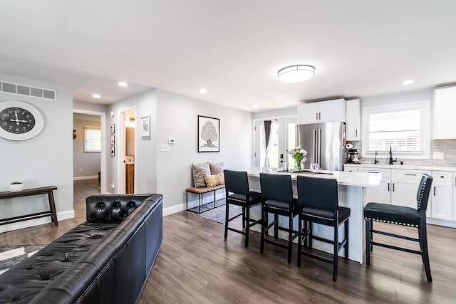 kitchen featuring freestanding refrigerator, a breakfast bar area, a kitchen island, white cabinets, and dark wood-style floors