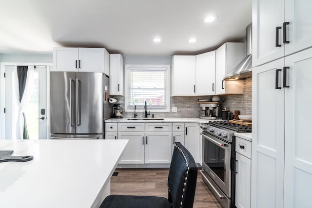 kitchen with premium appliances, a sink, light countertops, white cabinetry, and recessed lighting