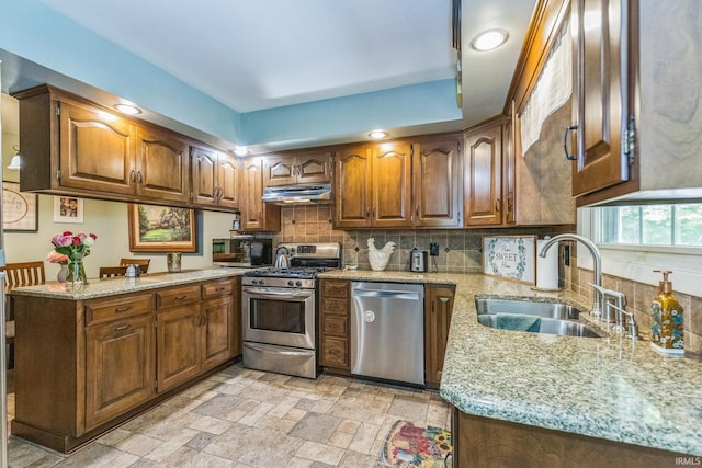 410 Longtree Ln, Logansport, IN 46947 - kitchen featuring appliances with stainless steel finishes, a sink, under cabinet range hood, backsplash, and light stone countertops