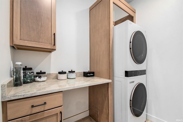 clothes washing area with stacked washer and clothes dryer and cabinet space