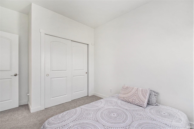 carpeted bedroom featuring a closet and baseboards