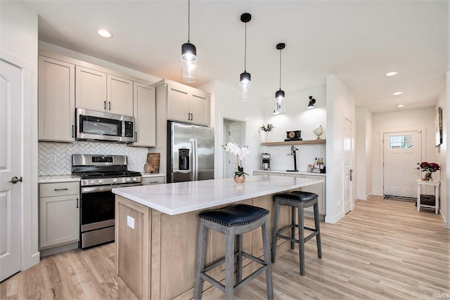 kitchen with appliances with stainless steel finishes, open shelves, backsplash, a kitchen island, and light wood-type flooring