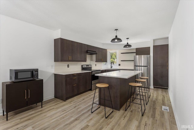 214 Mccutcheon Dr, Lafayette, IN 47909 - kitchen with appliances with stainless steel finishes, a breakfast bar, light wood-style floors, dark brown cabinetry, and light countertops