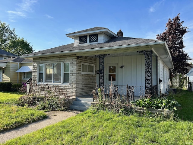bungalow featuring a chimney, a porch, a shingled roof, and stone siding