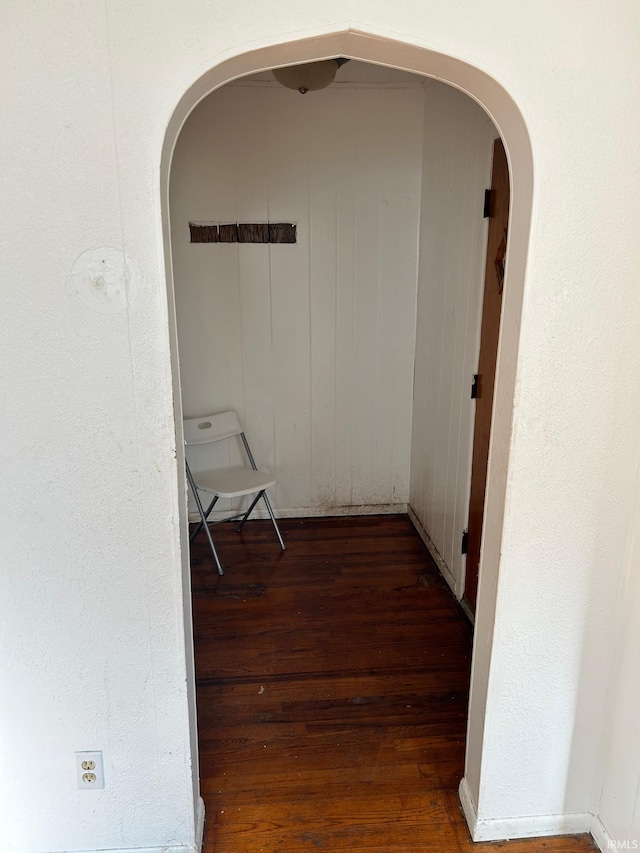 hallway featuring wood finished floors and arched walkways
