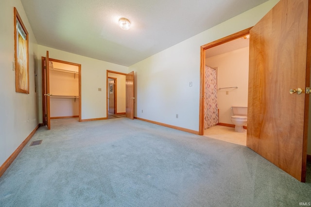 109 E Grant St, Lafontaine, IN 46940 - unfurnished bedroom featuring light carpet, baseboards, connected bathroom, and a walk in closet