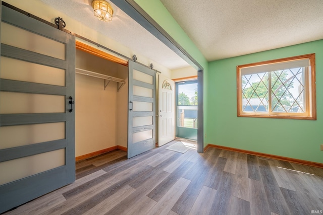 109 E Grant St, Lafontaine, IN 46940 - unfurnished bedroom with a textured ceiling, wood finished floors, baseboards, a barn door, and a closet
