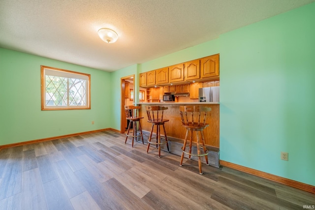 109 E Grant St, Lafontaine, IN 46940 - indoor bar with wood finished floors, stainless steel fridge with ice dispenser, baseboards, a textured ceiling, and black microwave