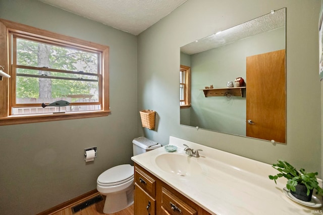 bathroom featuring toilet, a textured ceiling, vanity, baseboards, and wood finished floors