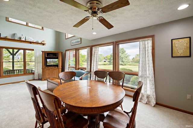 dining area featuring light colored carpet, baseboards, ceiling fan, a textured ceiling, and healthy amount of natural light