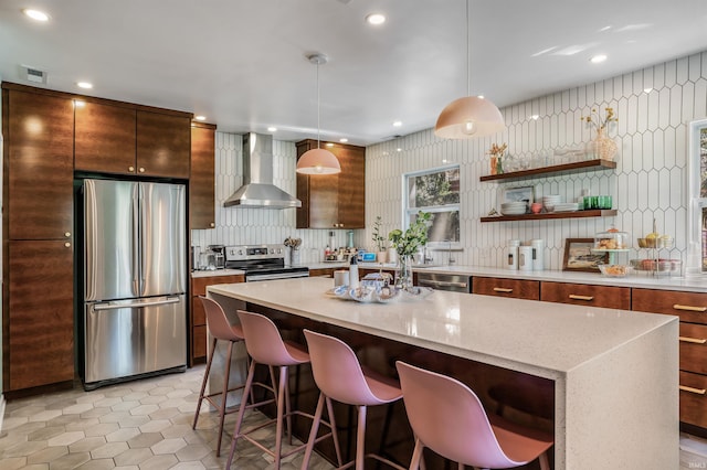 kitchen featuring appliances with stainless steel finishes, wall chimney range hood, light tile patterned floors, a center island, and a breakfast bar area