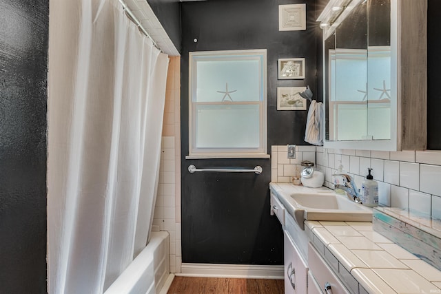 bathroom featuring wood finished floors, vanity, backsplash, and shower / bathtub combination with curtain