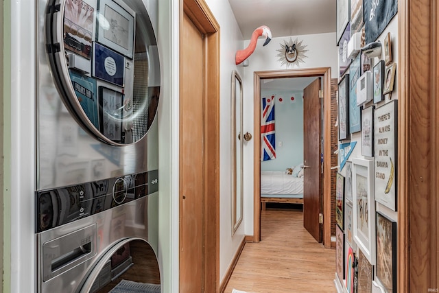 laundry area with stacked washer / dryer and light wood-style flooring