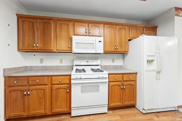 kitchen featuring white appliances, light countertops, brown cabinetry, and light wood-type flooring