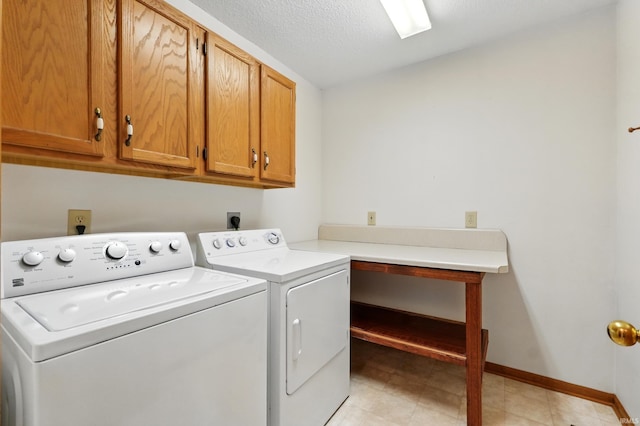 laundry area with cabinet space, washer and dryer, baseboards, and a textured ceiling
