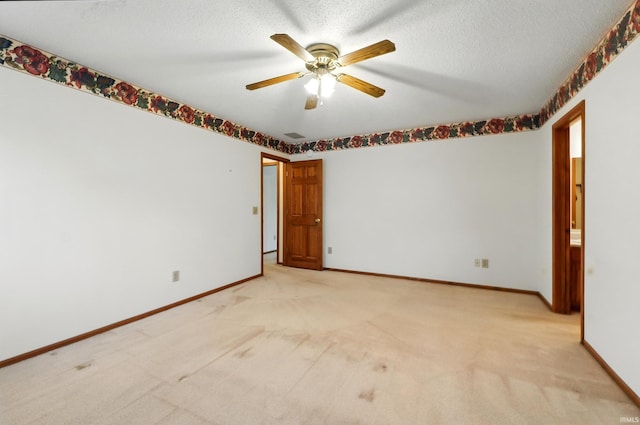 unfurnished room featuring ceiling fan, light colored carpet, baseboards, and a textured ceiling