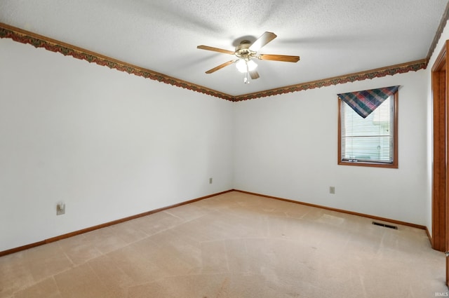 empty room featuring ceiling fan, baseboards, light colored carpet, and a textured ceiling