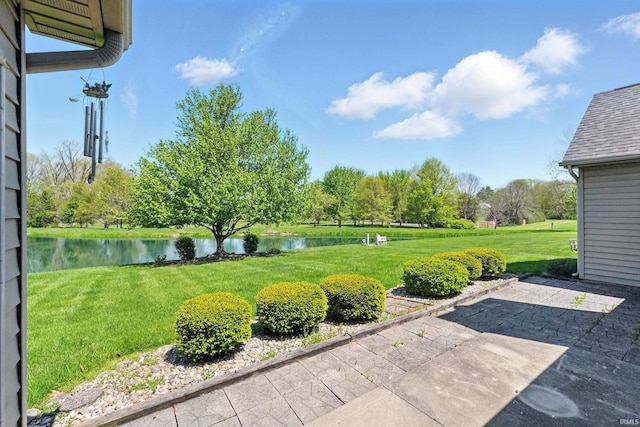 view of grassy yard featuring a water view and a patio area