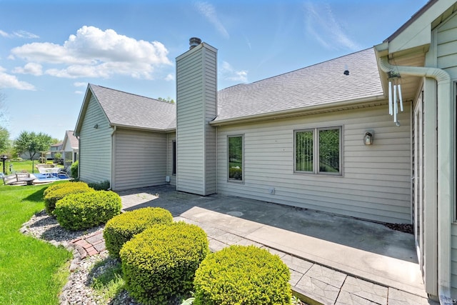 rear view of property with a patio area, a chimney, and roof with shingles