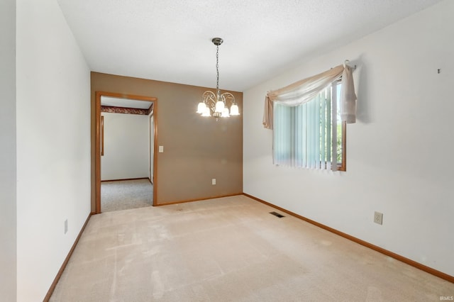 spare room featuring carpet, a chandelier, and baseboards