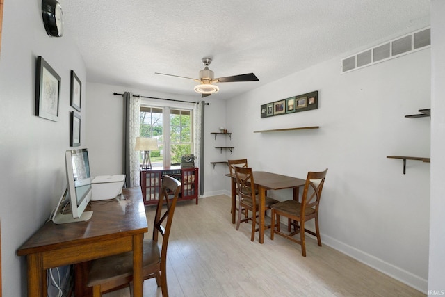dining room featuring a ceiling fan, light wood-style floors, a textured ceiling, baseboards, and a desk