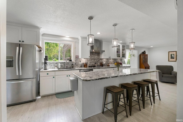 kitchen with stainless steel appliances, light wood-type flooring, decorative backsplash, a center island, and a textured ceiling