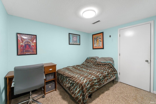 carpeted bedroom featuring an office area and a textured ceiling