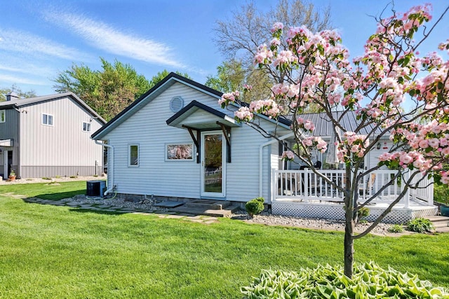 view of front of house featuring a front yard, central air condition unit, and a wooden deck