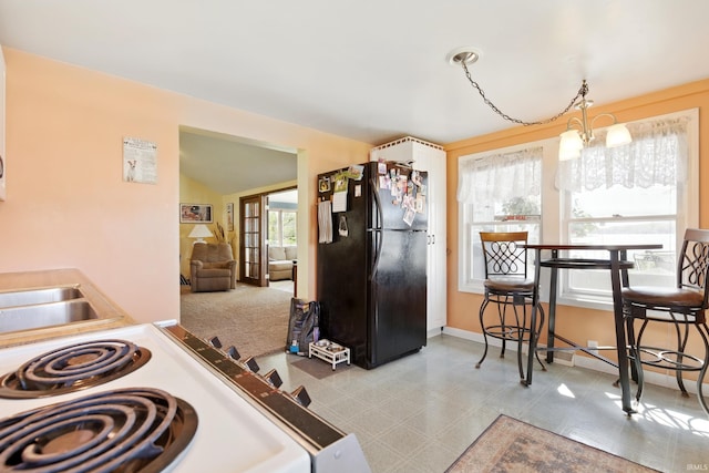 kitchen with freestanding refrigerator, white electric stove, tile patterned floors, and vaulted ceiling