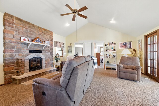 living room with carpet, a ceiling fan, high vaulted ceiling, and a stone fireplace
