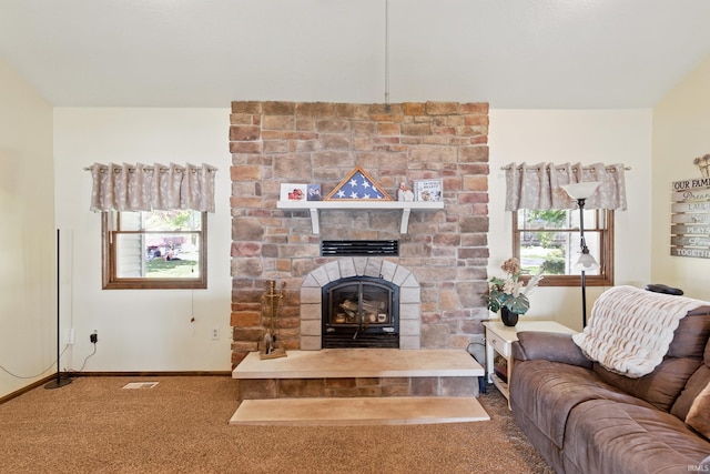 carpeted living area featuring a stone fireplace and baseboards