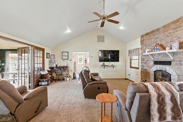 living area with carpet floors, ceiling fan, high vaulted ceiling, and a stone fireplace