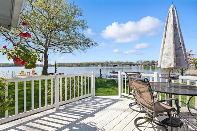 deck with a water view, a boat dock, and a lawn