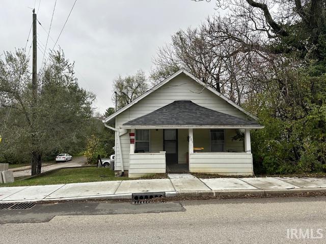 bungalow-style home with covered porch and a shingled roof