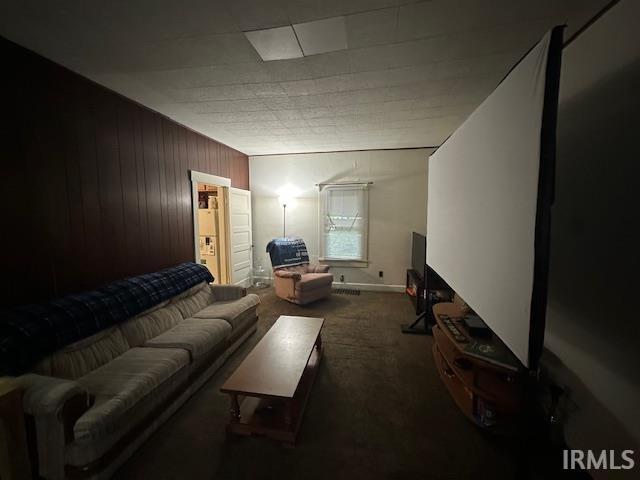 carpeted living room with wood walls