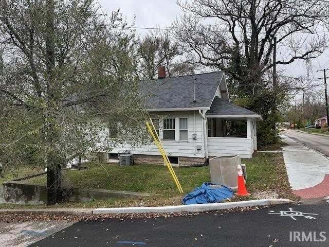 view of front of property with a chimney, central air condition unit, roof with shingles, and a sunroom
