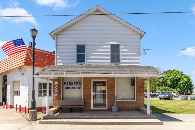 6115 N State Road 327, Orland, IN 46776 - view of front facade featuring a porch, a shingled roof, and brick siding