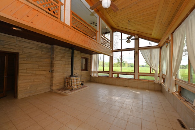 unfurnished sunroom with a wood stove, tile patterned floors, wooden ceiling, and high vaulted ceiling
