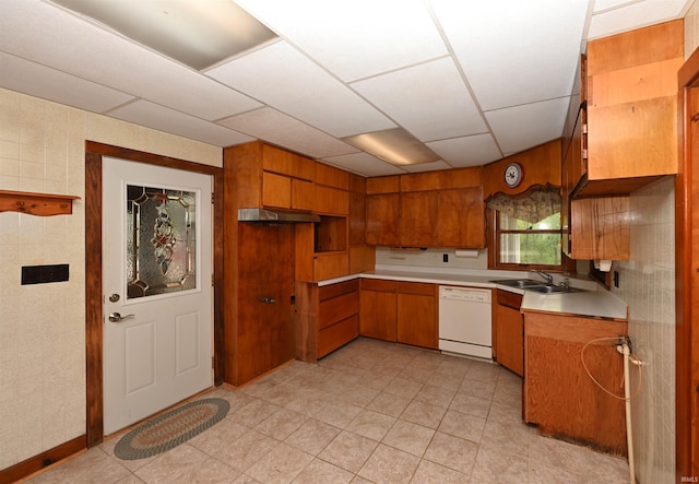 kitchen featuring dishwasher, brown cabinets, light countertops, a sink, and light tile patterned flooring